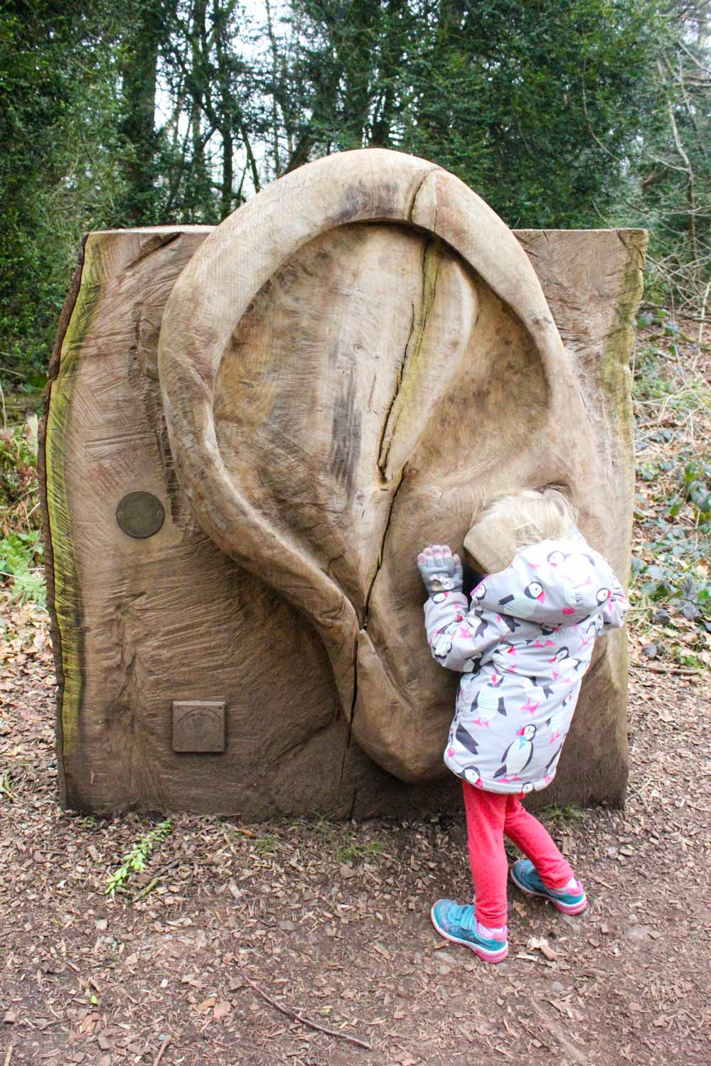 My daughter listens to a giant carved wooden ear statue at Tyntesfield National Trust