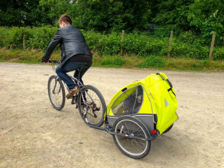 My husband cycling at Bluestone Wales with my baby daughter in a trailer being pulled behind - discovering the Blue Lagoon Bluestone on our visit with a baby