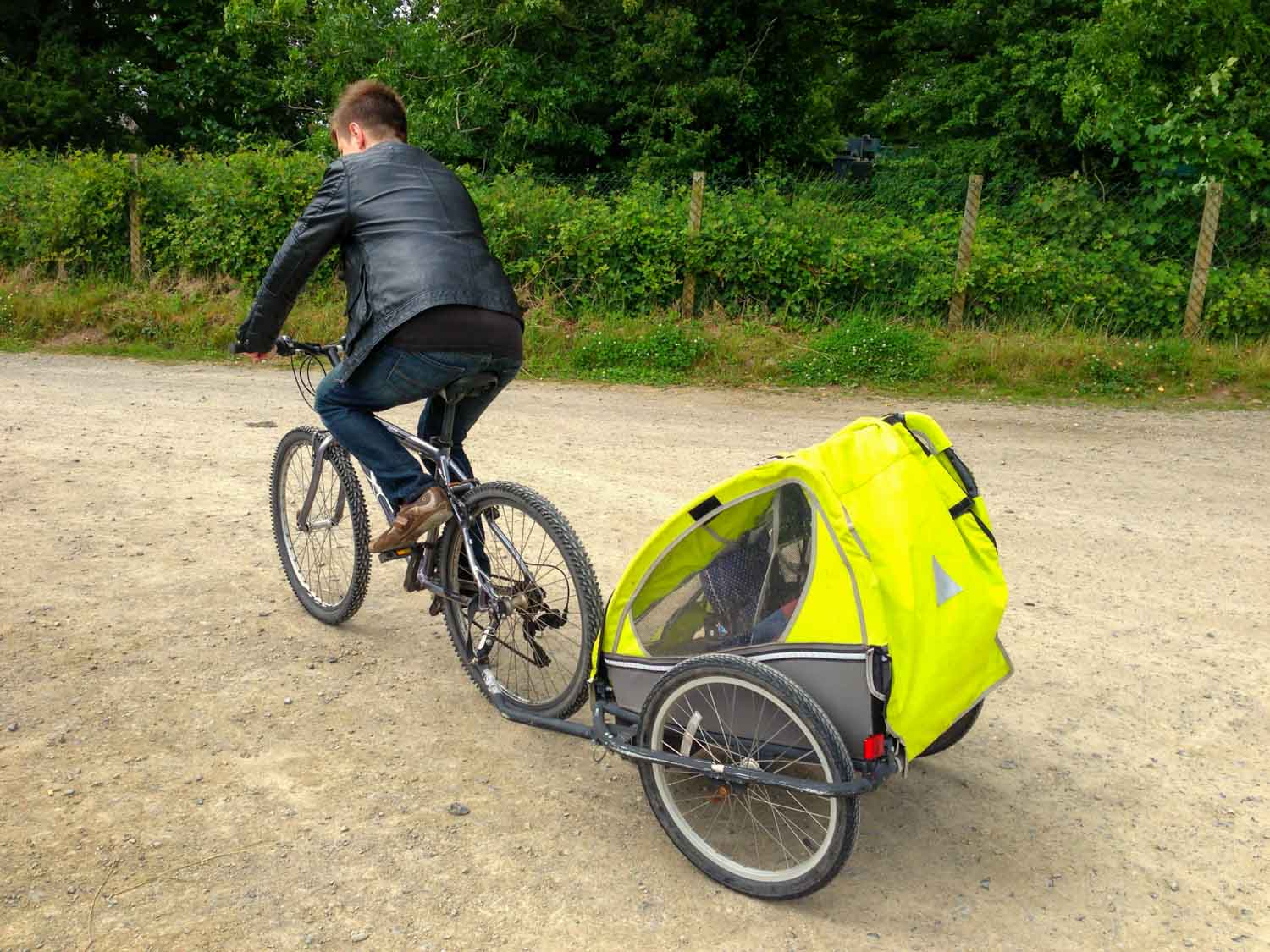 My husband cycling at Bluestone Wales with my baby daughter in a trailer being pulled behind - discovering the Blue Lagoon Bluestone on our visit with a baby