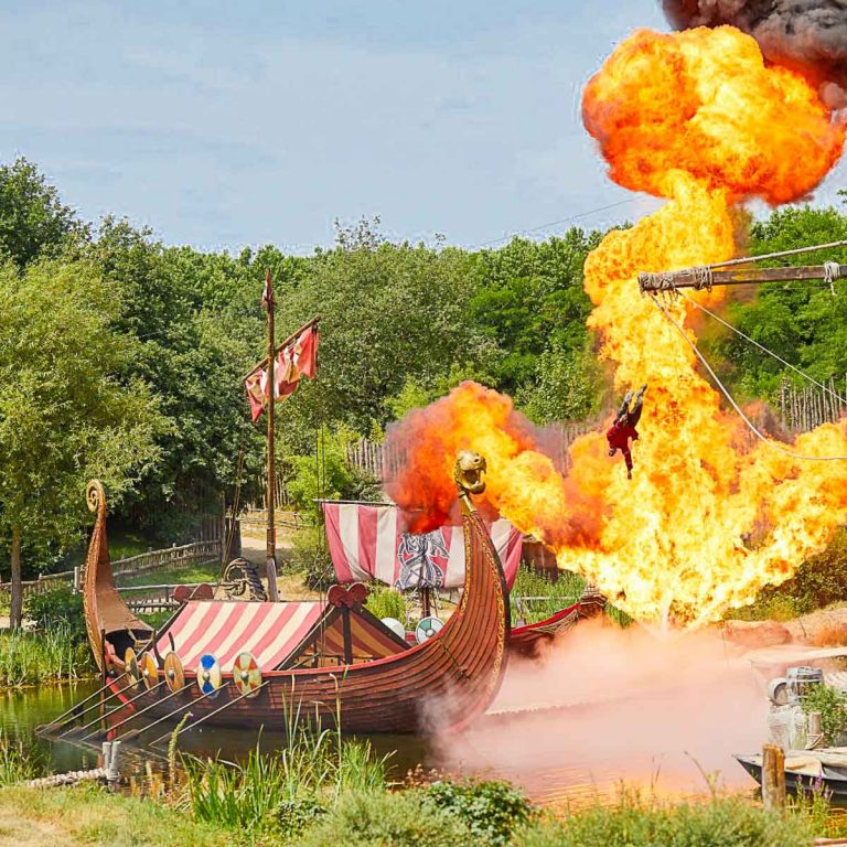Pyrotechnics behind a Viking Ship as one of the actors flies through the air in Les Vikings show at Puy du Fou, France - my tips for Puy du Fou with kids
