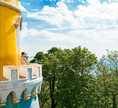 View of a woman and young girl by the yellow tower of the Pena Palace in Sintra, Portugal - one of the trips taken with my daughter as part of my award-winning family travel blog MummyTravels
