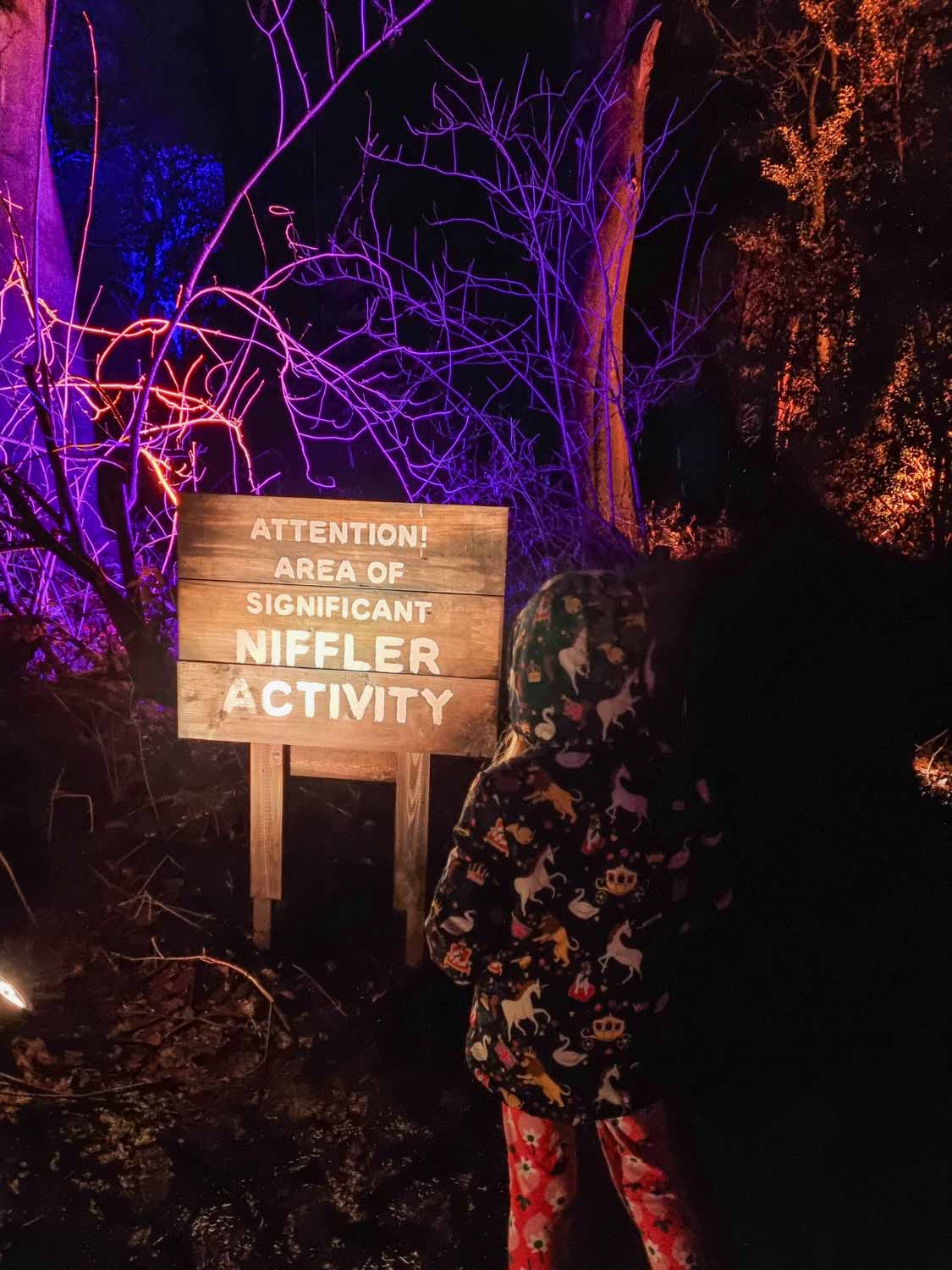 My daughter looks at a sign reading 'Attention Area of Significant Niffler Activity' - my Harry Potter Forbidden Forest review