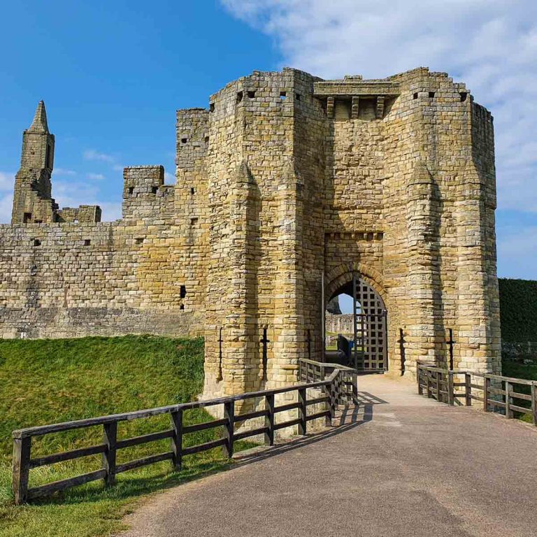 Gatehouse entrance to Warkworth Castle Northumberland with some of the towers seen in the distance against a blue sky - for the best things to do in Northumberland with kids, you can't miss some of the historic castles
