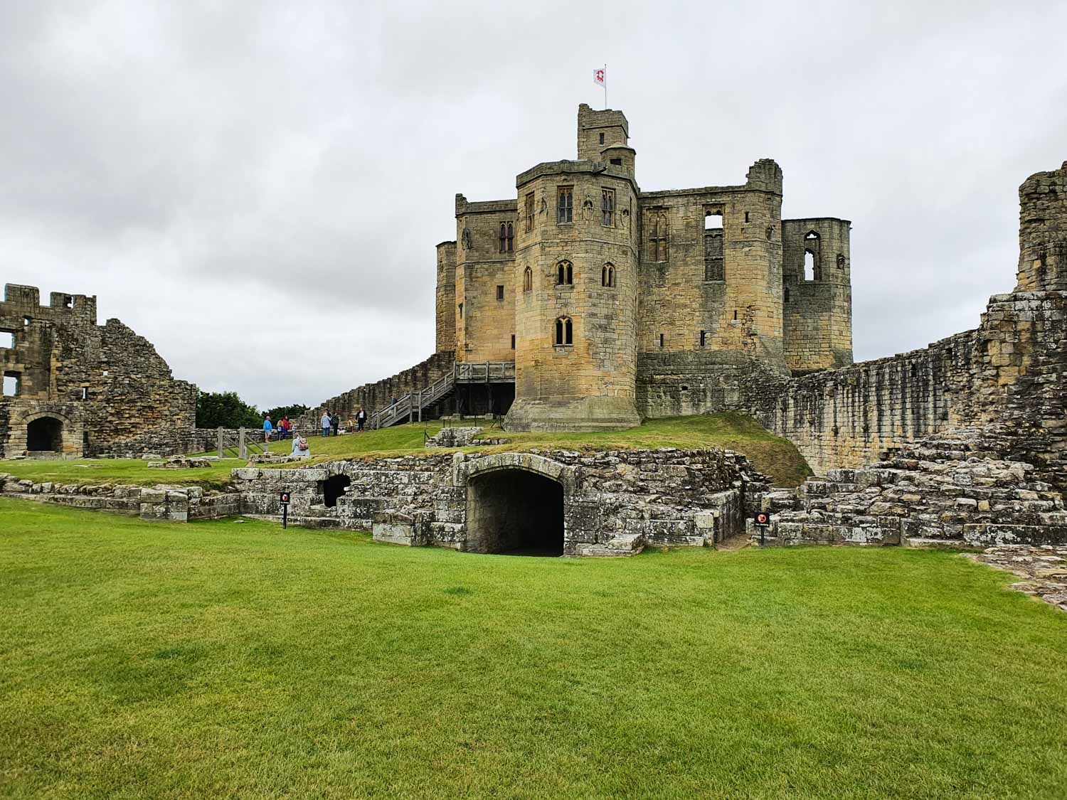 View across the grass of the inner court to the huge stone keep at Warkworth Castle Northumberland on a cloudy day - my review of a visit to Warkworth Castle with kids