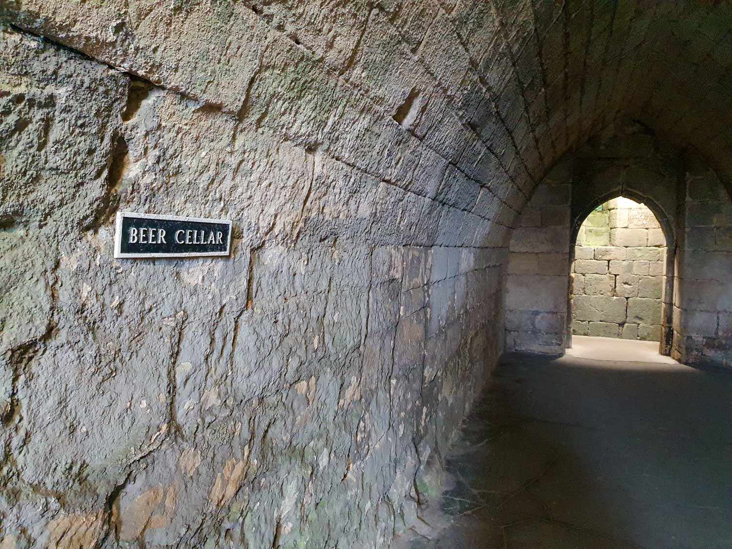 Stone tunnel with a sign reading Beer Cellar under the huge Keep at Warkworth Castle, Northumberland - visiting Warkworth Castle with kids