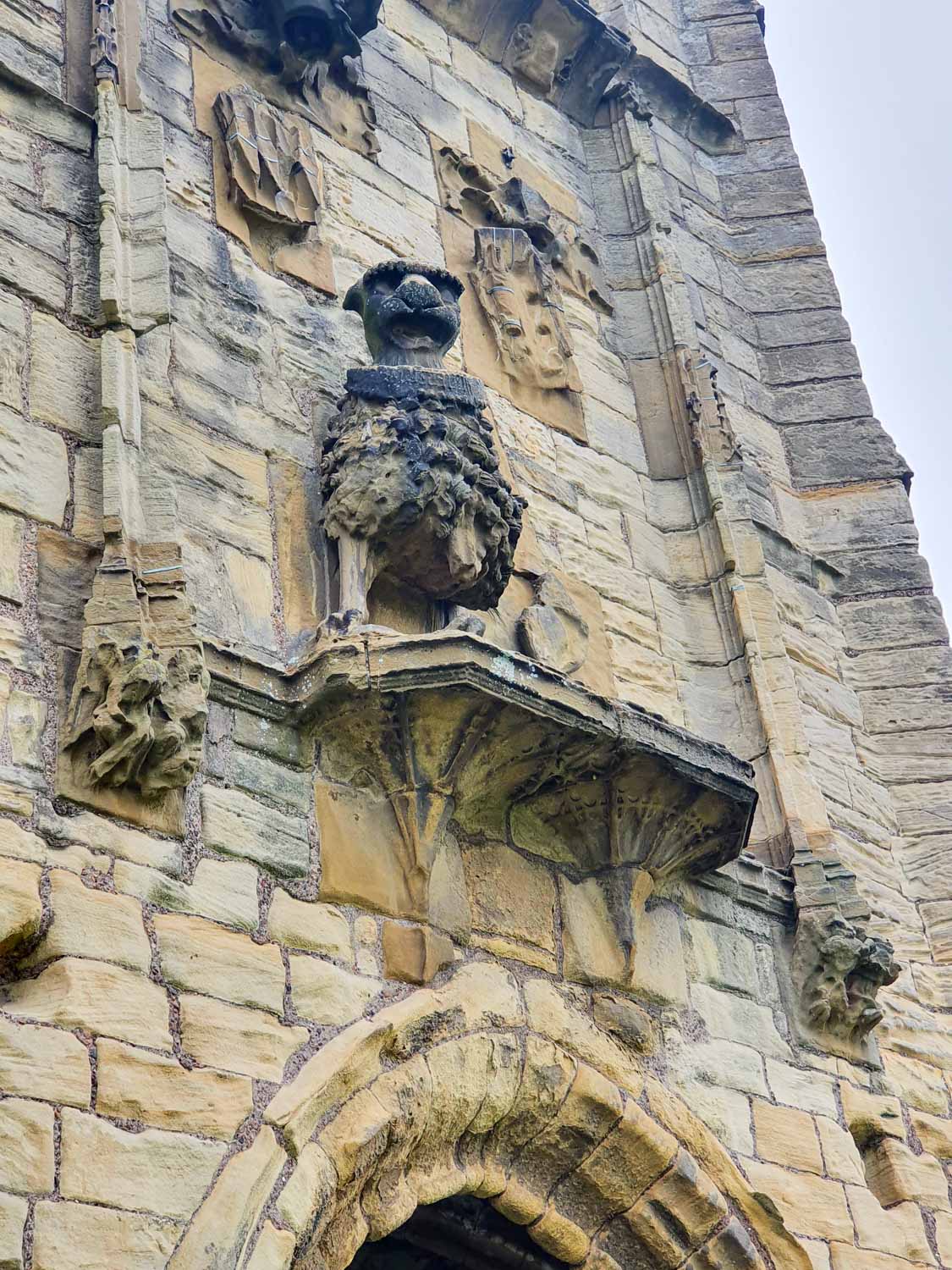 Heraldic lion statue under stone shields on one of the towers at Warkworth Castle, Northumberland - one of many details to spot at Warkworth Castle with kids