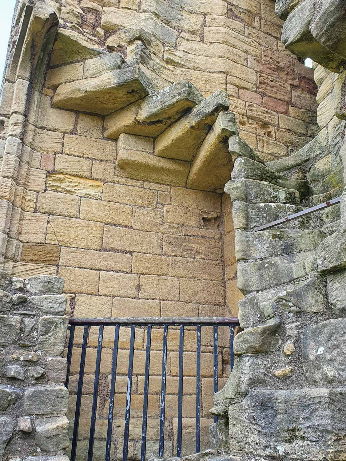 View of the remains of a stone staircase in one of the ruined towers, with a gate preventing anyone getting too close - visiting Warkworth Castle with kids