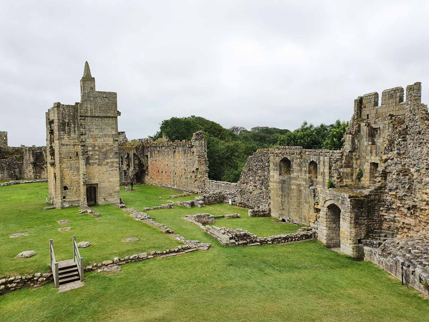 A view across the inner court at Warkworth Castle, Northumberland, including the outlines of old rooms, the remains of a tower standing alone and ruined walls - my visit to Warkworth Castle for kids