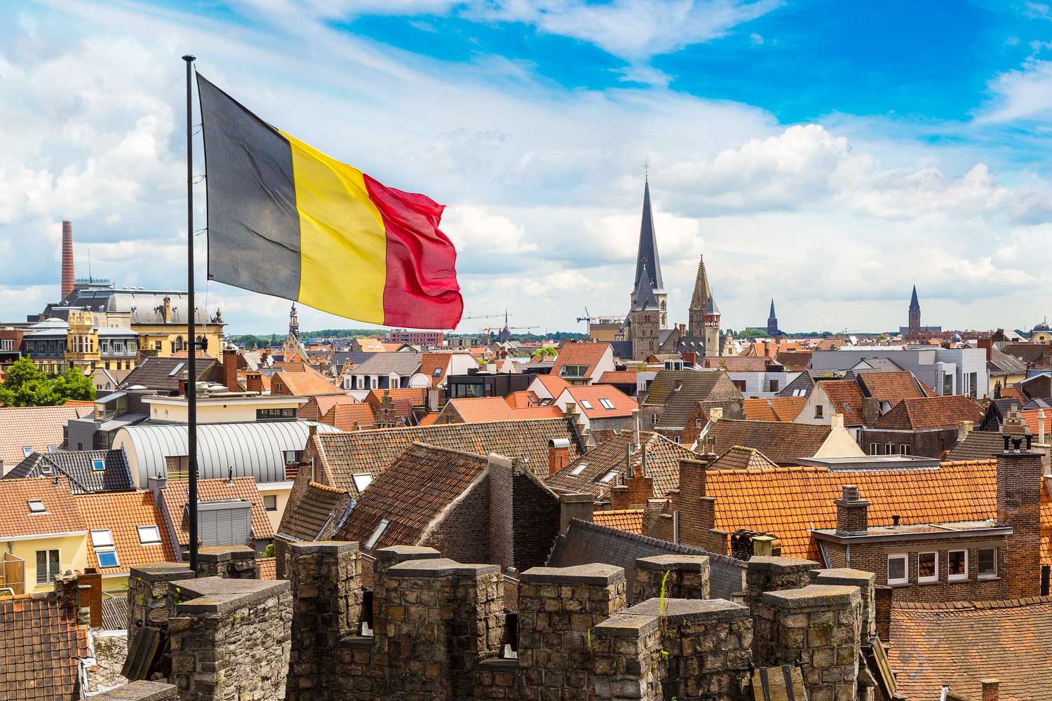 View across the rooftops of Ghent from the medieval castle Gravensteen on a summer day with the Belgian flag flying in the foreground - my guide to Belgium with kids