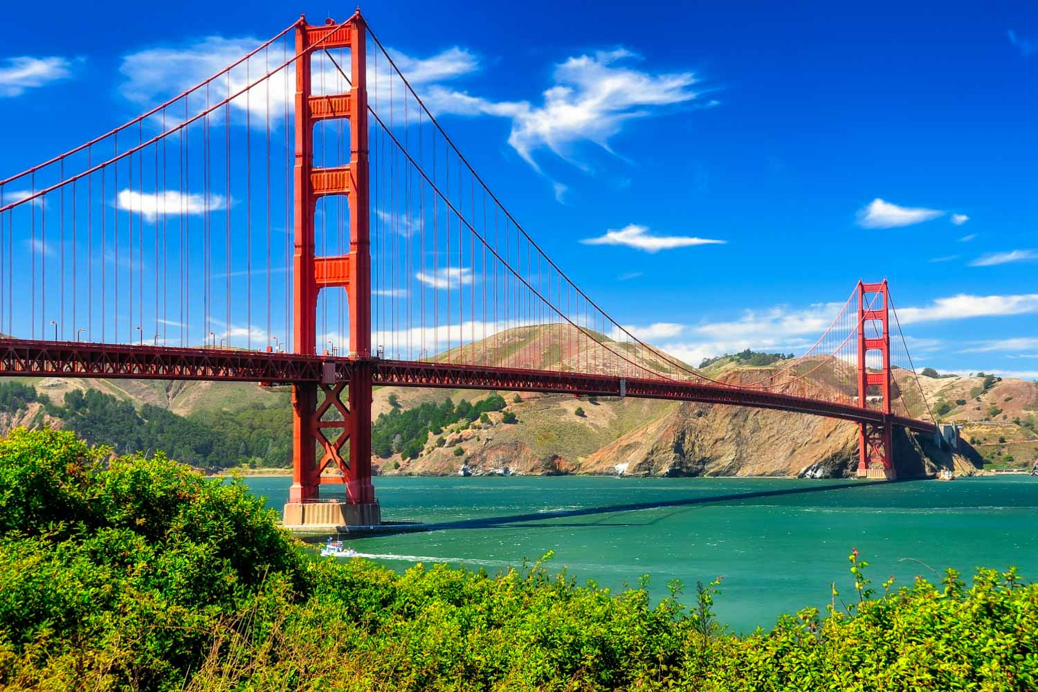 View across the Golden Gate bridge in California on a sunny day as a small boat passes underneath - one of my 63 things to do in San Francisco with kids, my pick of the different places, tours and attractions in San Francisco for a family holiday, from parks to museums, activities and playgrounds.