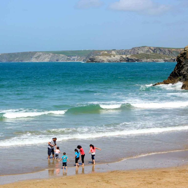 A family paddling on the beach in Newquay - my top things to do in Cornwall with kids