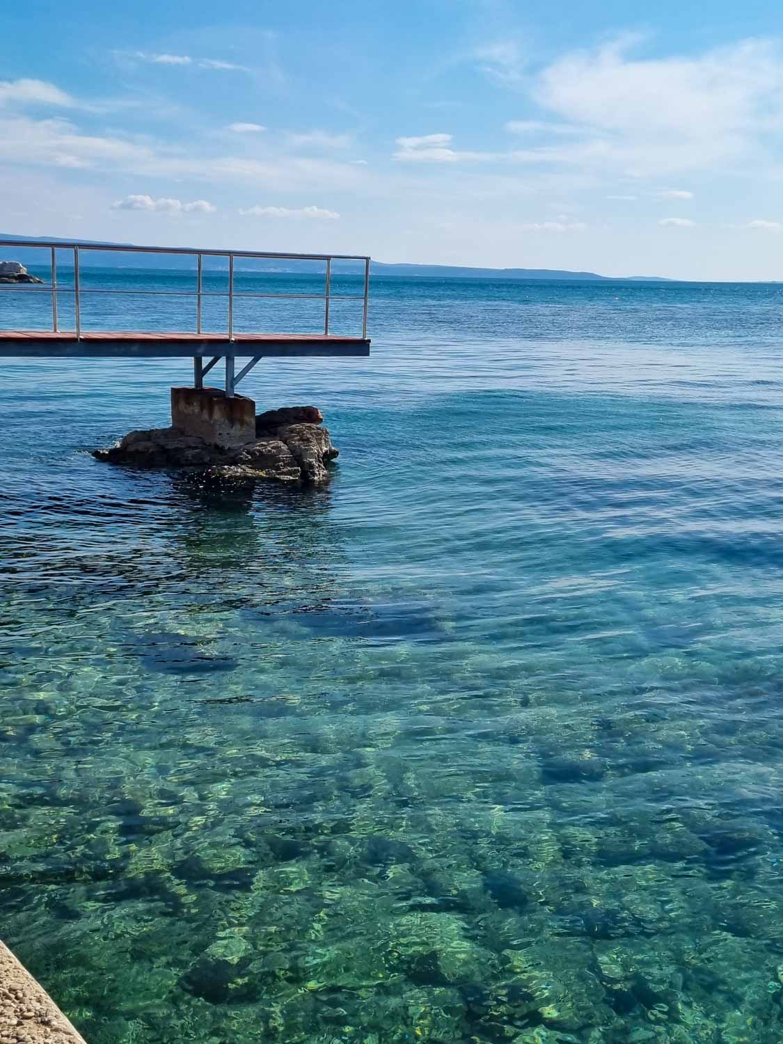 View of a diving platform over the clear turquoise sea near Ovcice Beach at Split - a visit to the small beach is one of the best things to do in Split for kids