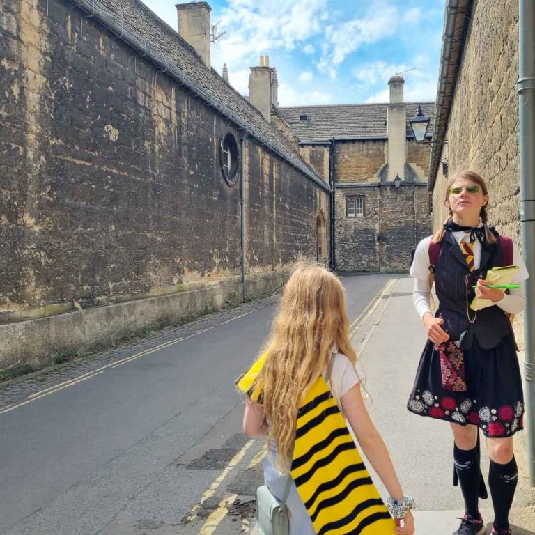 The guide on our Oxford Harry Potter walking tour with my daughter, wearing scarf in Hufflepuff colours of black and yellow, along our route through the back streets of Oxford