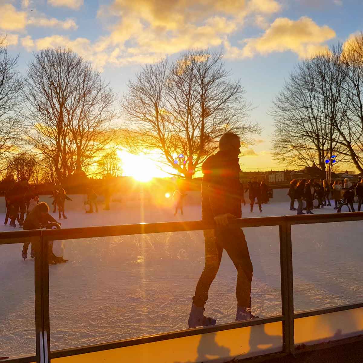People silhouetted against the setting sun on one of the pop-up Christmas ice rinks in London at Hampton Court Palace - the best places to ice skate in London with kids