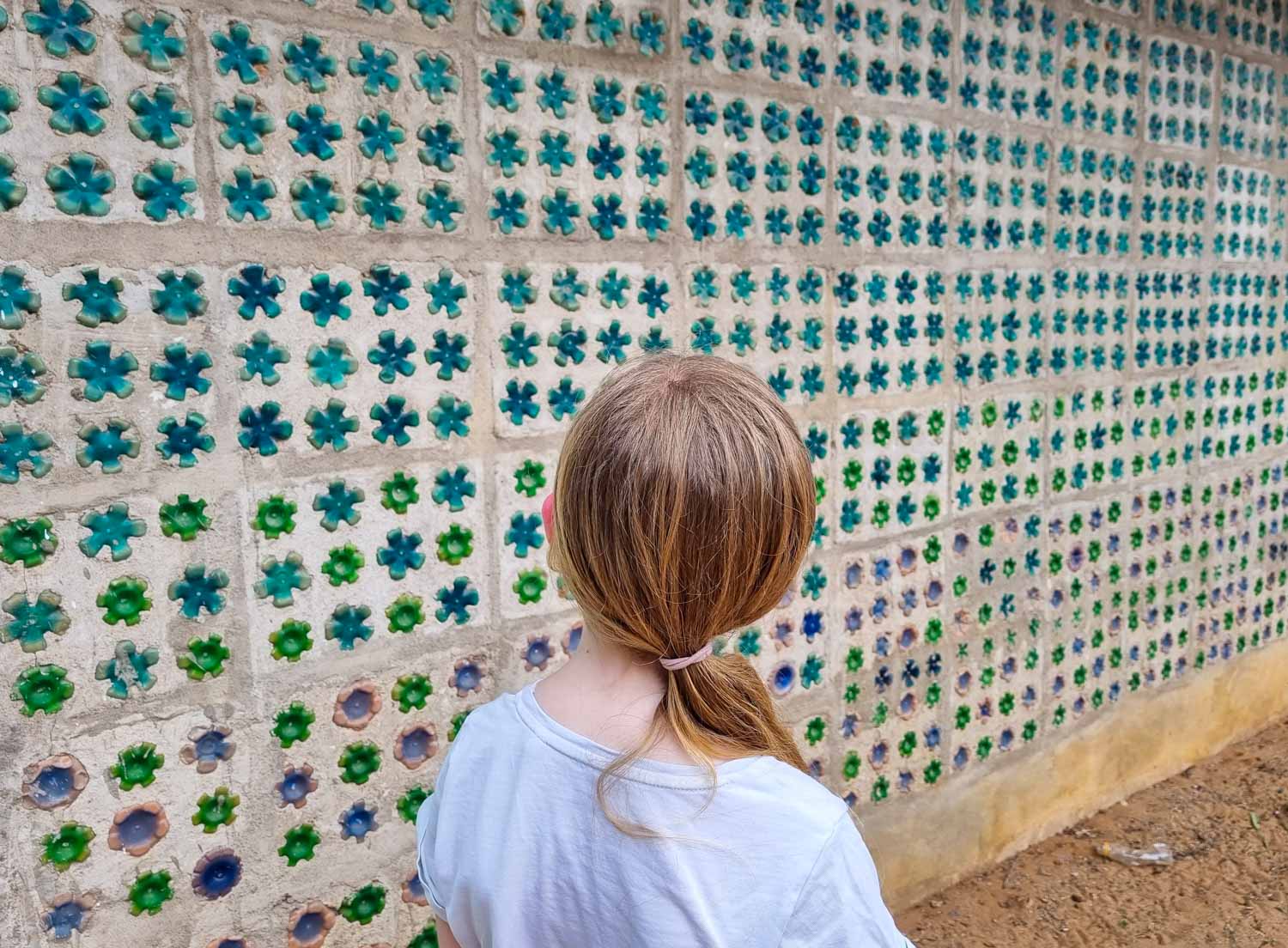 My daughter looks at a wall containing plastic bottles, one of the sustainable ways to combat plastic waste at EcoWorld Watamu during our stay at Hemingways Watamu with kids