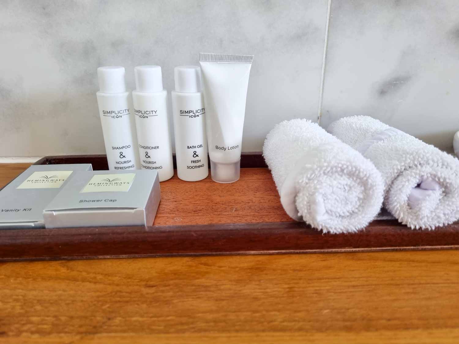 Close-up of toiletries and amenity kids with rolled-up towels in the bathroom of our Deluxe Ocean View room at Hemingways Watamu in Kenya