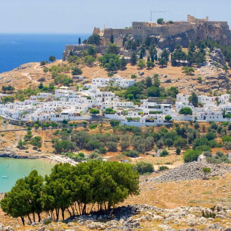 View across the beach and village of Lindos to Lindos Acropolis - my tips for visiting the Acropolis of Lindos with kids