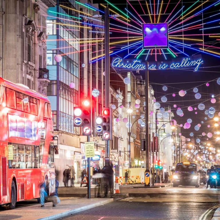 Illuminated sign reading Christmas is calling with lights in the background and a red double decker bus - my tips on the best London Christmas lights walking route with kids or without