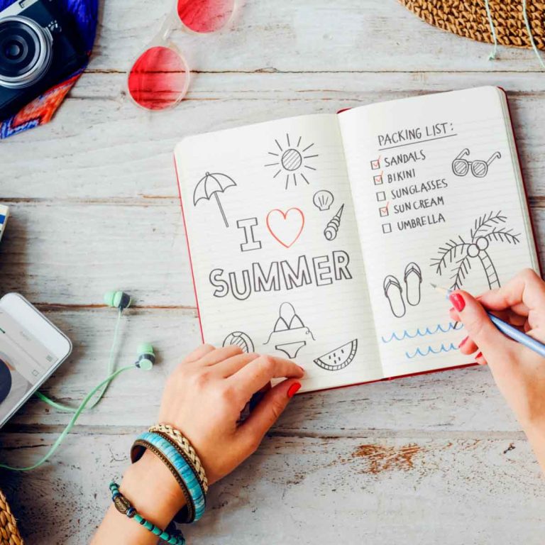 Woman writing a summer beach holiday list - my pre-holiday checklist tips including the essential things to do before you travel