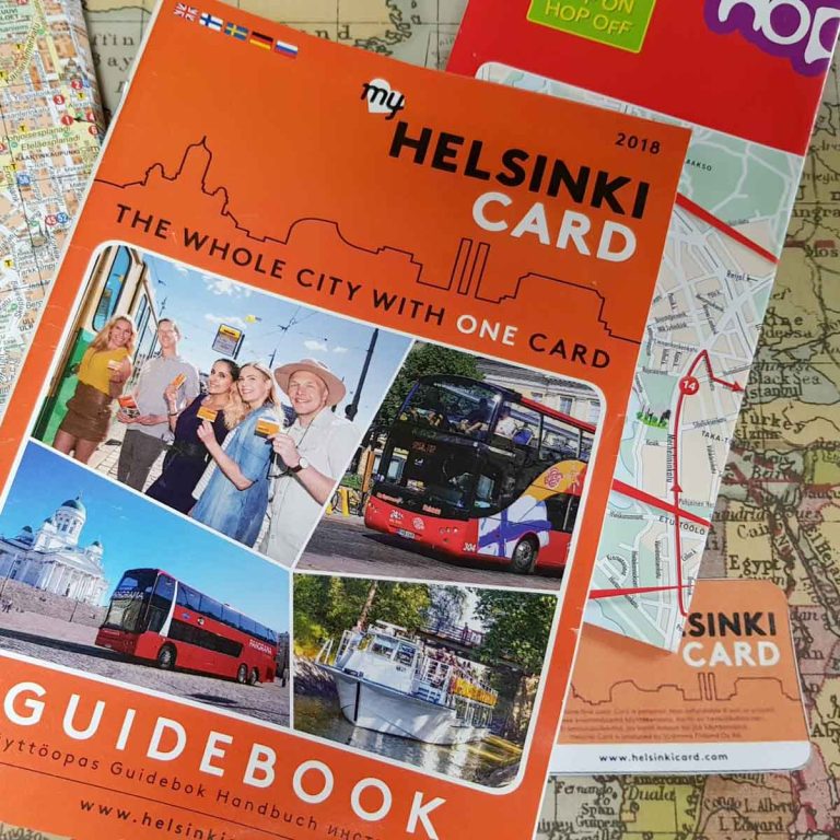 The Helsinki card guidebook with card and assorted maps and leaflets on a map background - is the Helsinki card worth it? My review of the Helsinki card - the city pass, if you're looking to save money in Helsinki