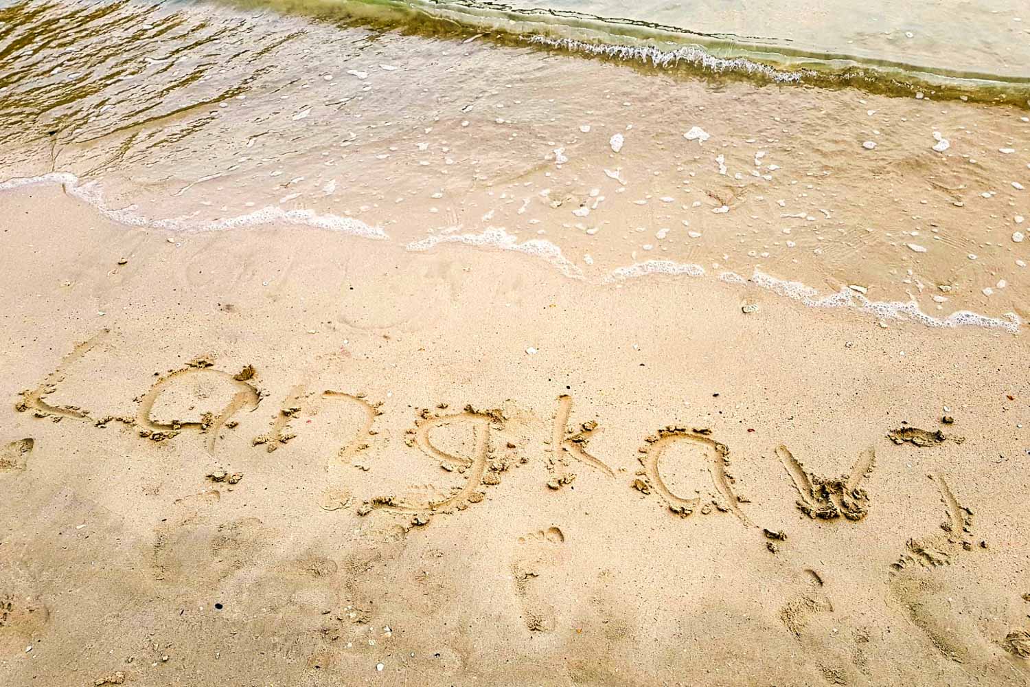 The word Langkawi drawn in the sand of a beach - my top things to do and see in Langkawi with kids