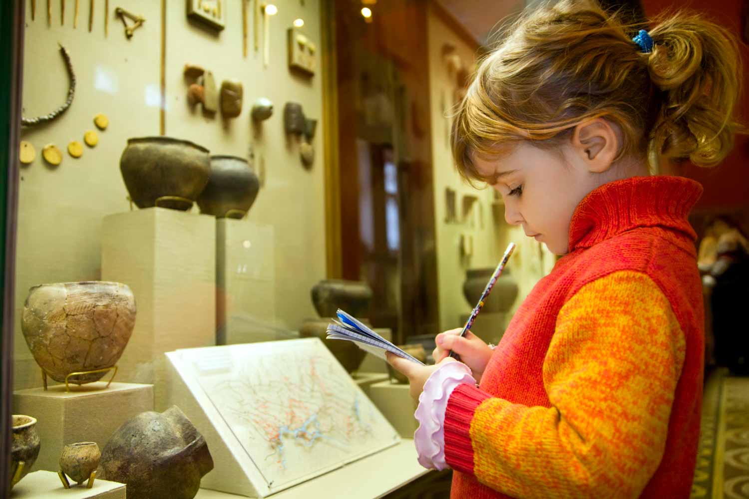 Girl carrying out an activity in a museum, standing in front of a display case - my ultimate guide to London's museums and tips on the best London museums for toddlers and kids
