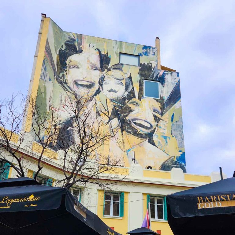 View of a piece of street art in Psiri in Athens using mirrors as well as smiling female faces and yellow sections - the final stop on a street art tour of Athens with kids