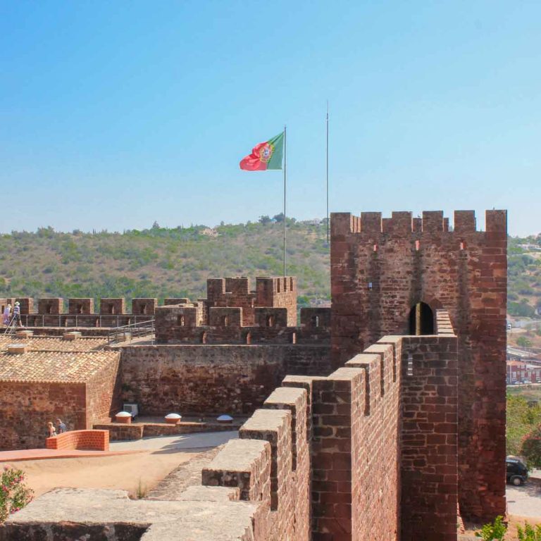 A Portuguese flag flies over the battlements of Silves Castle during a day out in the Algarve with kids
