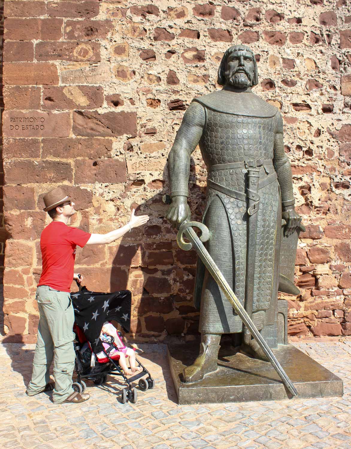 My husband and daughter in a buggy next to a huge statue of Sancho I outside Silves Castle during a day out in the Algarve with kids