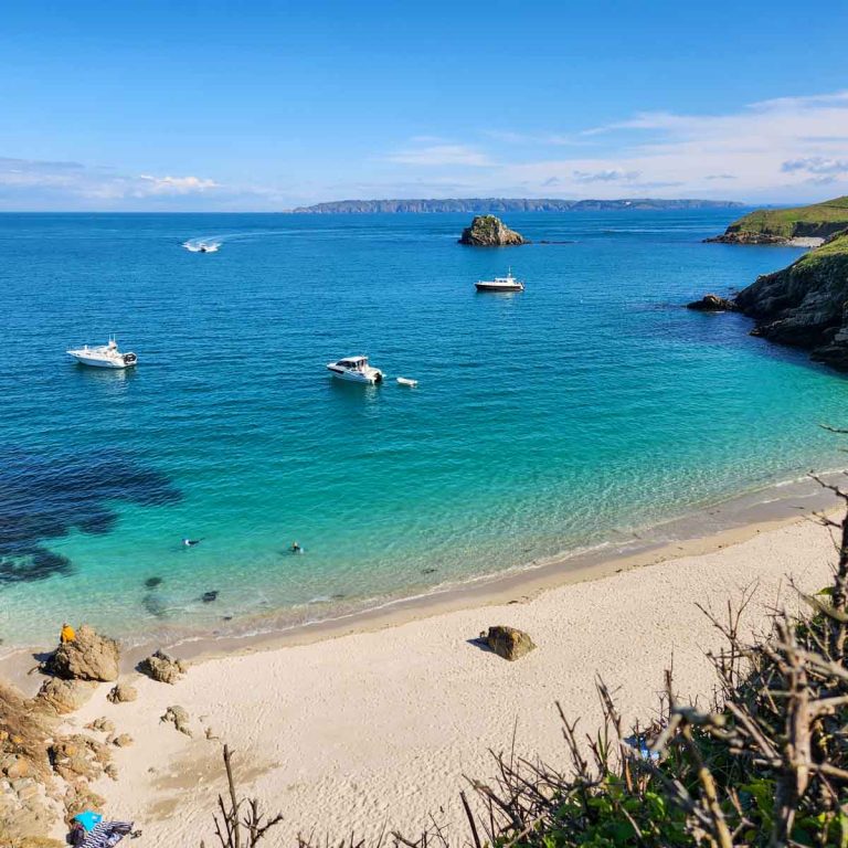 View down to Belvoir Beach on Herm with turquoise water and boats in the distance - one of many great things to do in Guernsey with kids