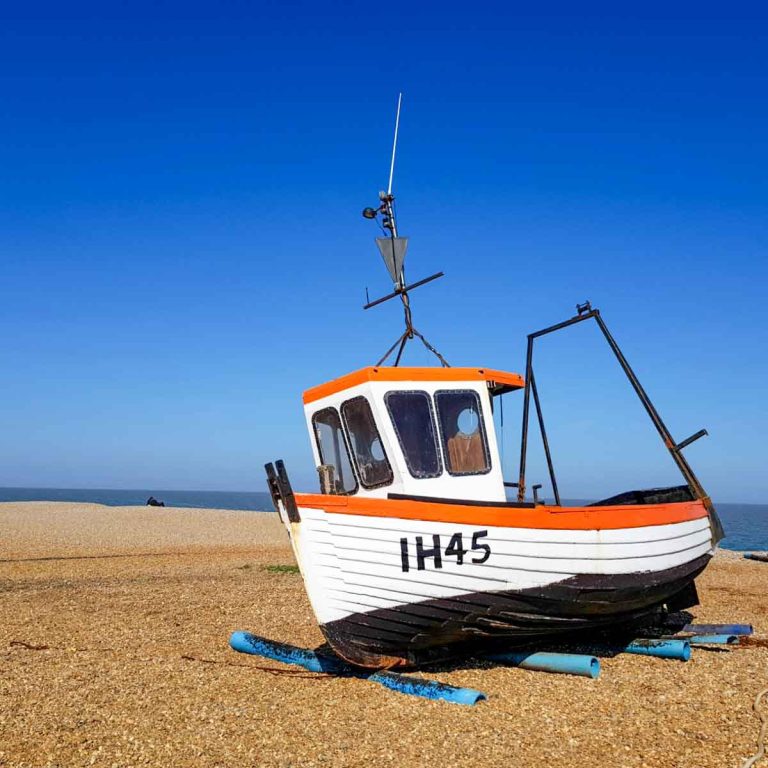 A boat beached on the shingle at Aldeburgh against a bright blue sky - one of my things to do in Aldeburgh with kids if you're visiting Suffolk
