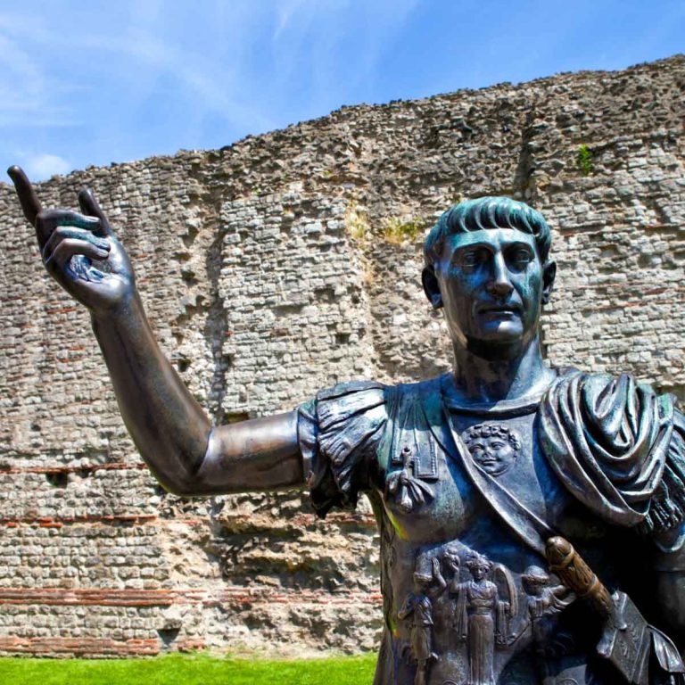 A statue of Roman Emperor Trajan with remains of London Wall which was first built by the Romans in the 2nd and 3rd Centuries AD - the best Roman places to visit in UK