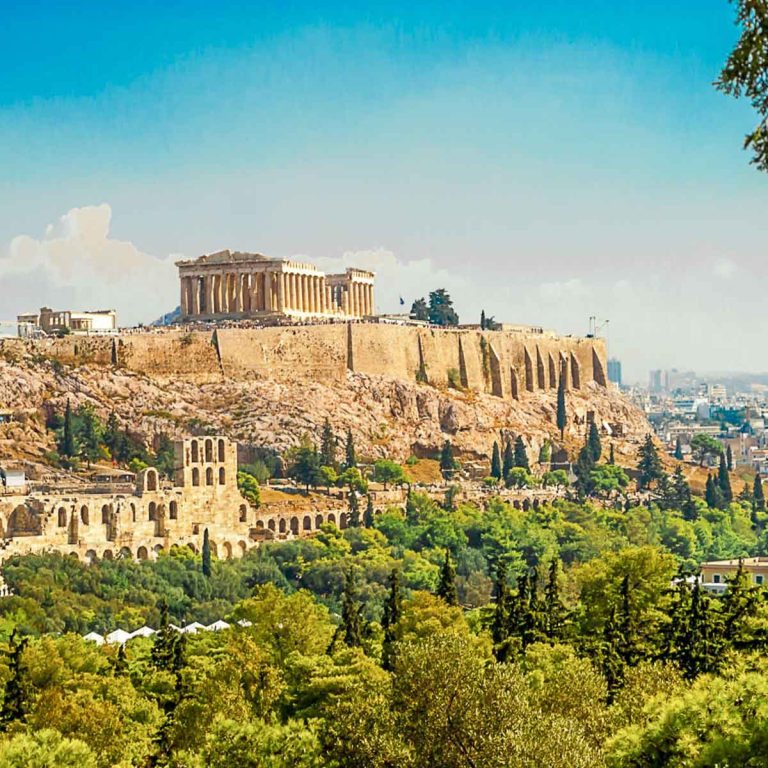 View up to the Acropolis of Athens with the ruined buildings on the hilltop and green trees below - a two-day itinerary for visiting Athens with a baby