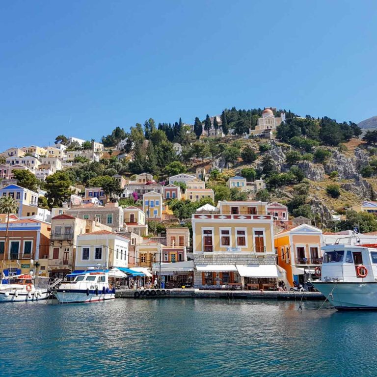 Ferry in front of the Italian influenced buildings in the harbour at Symi - 13 reasons to go Greek island hopping with kids