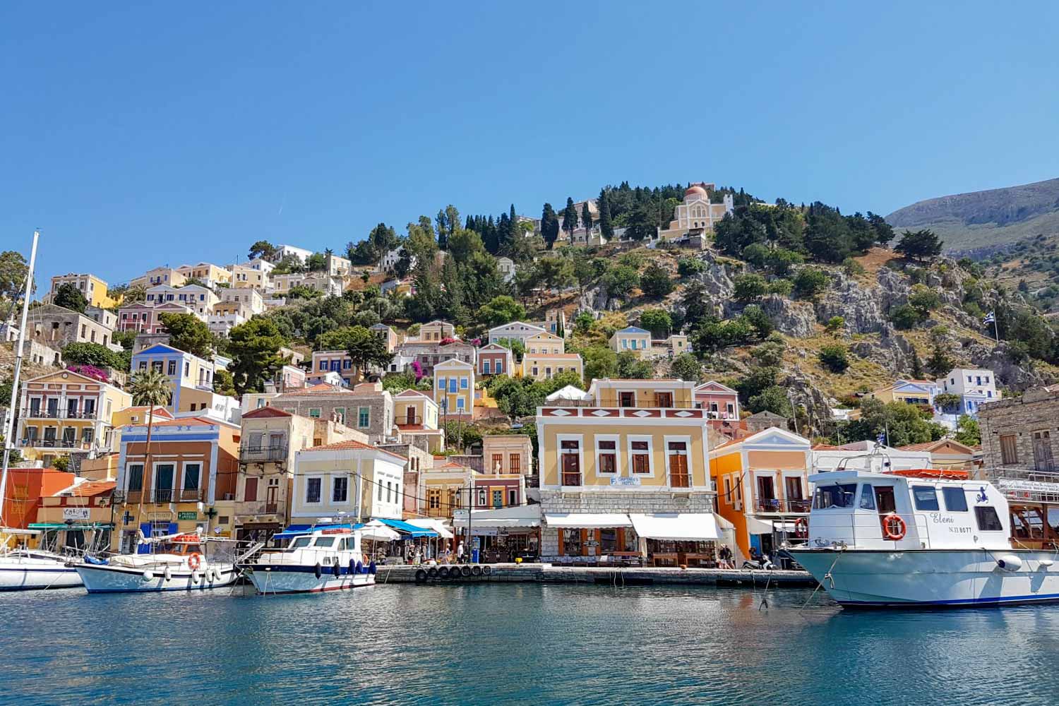 Ferry in front of the Italian influenced buildings in the harbour at Symi - 13 reasons to go Greek island hopping with kids