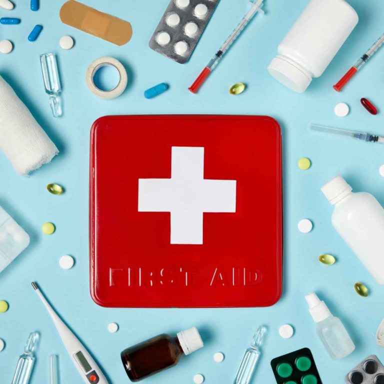 A retro style tin marked first aid case surrounded by medicine and bandages - my essential child first aid kit and downloadable checklist