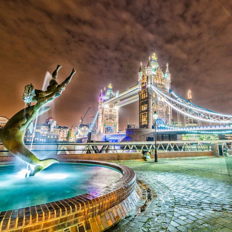View of the dolphin fountain and Tower Bridge lit up at night - my tips for the best things to do in the evening in London with kids