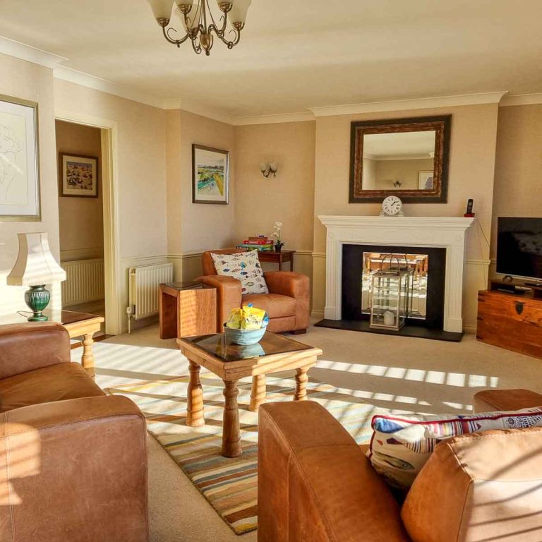 View of the living area with brown leather chairs, fish cushions and TV in the penthouse at the Beachcroft hotel Felpham - my review of a stay at the Sussex hotel with kids