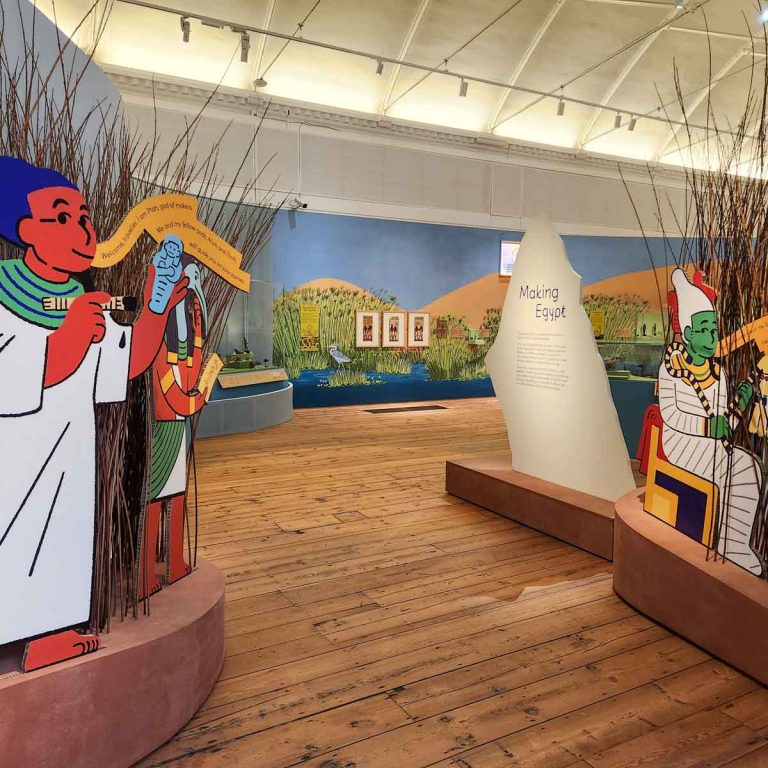 Entrance to the Making Egypt exhibition with cartoon-style Ancient Egyptian characters and room decorated like the Nile - my Making Egypt review of the new Young V&A exhibition