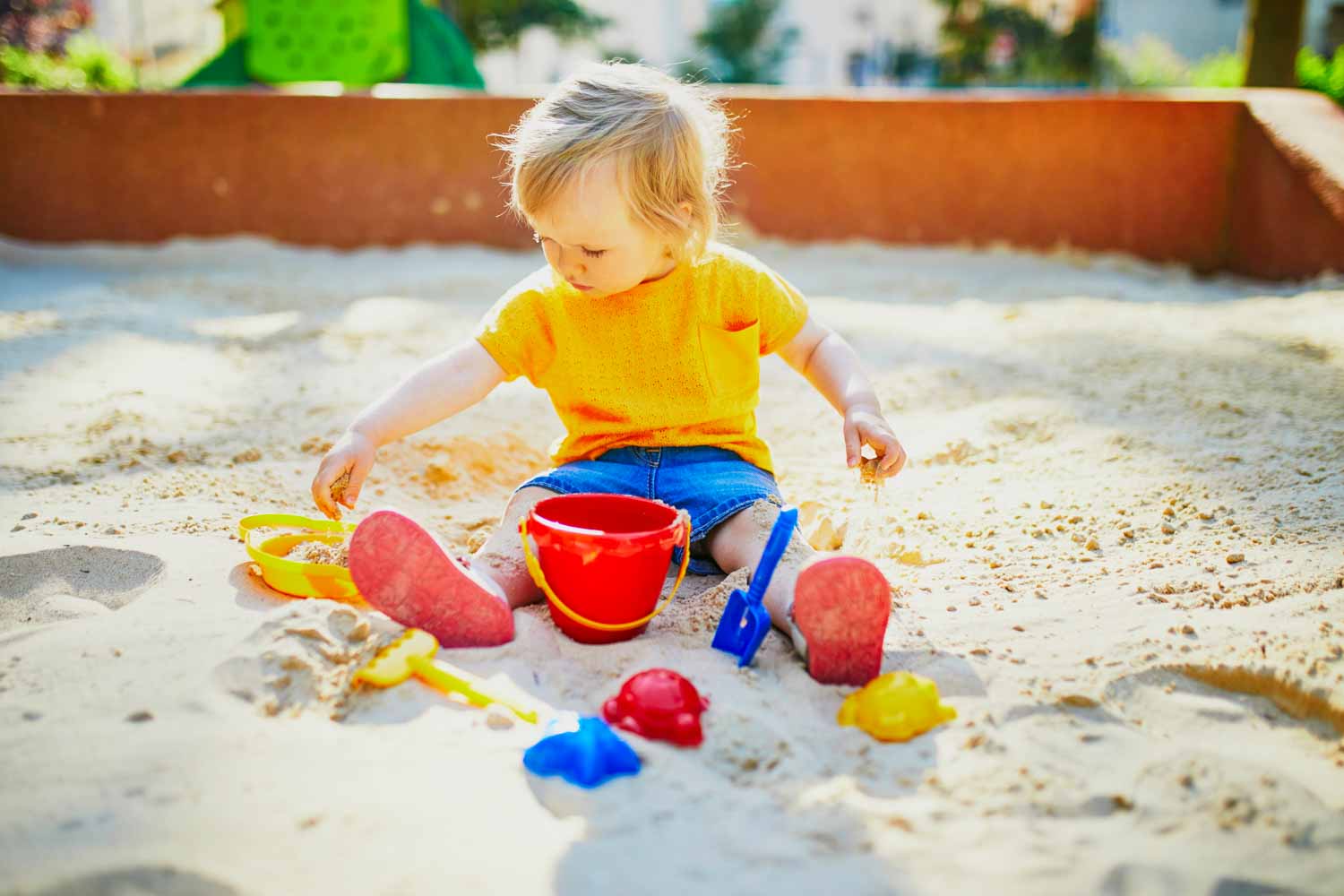 Young girl plays with sand toys in a playground sandpit - my pick of the best playgrounds in London 