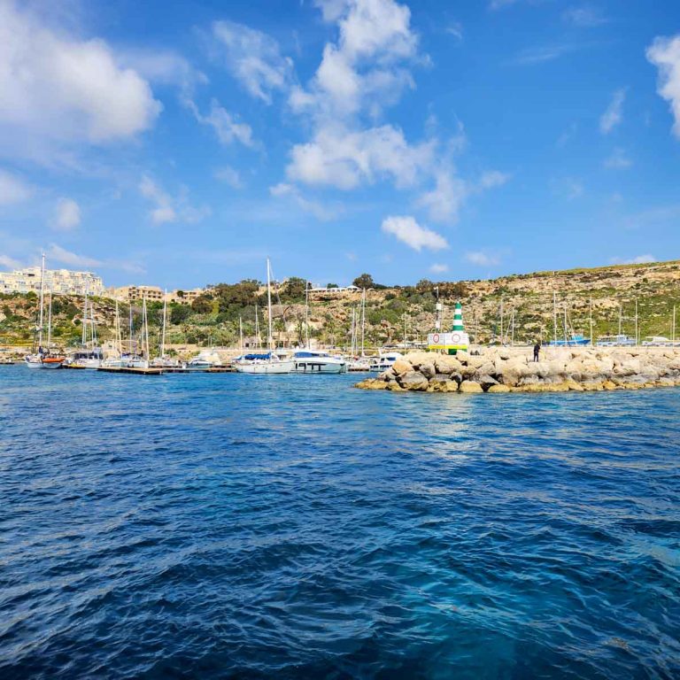 View of the coast with yachts moored up on the blue sea - my review of a Malta boat trip with kids to Gozo and Comino