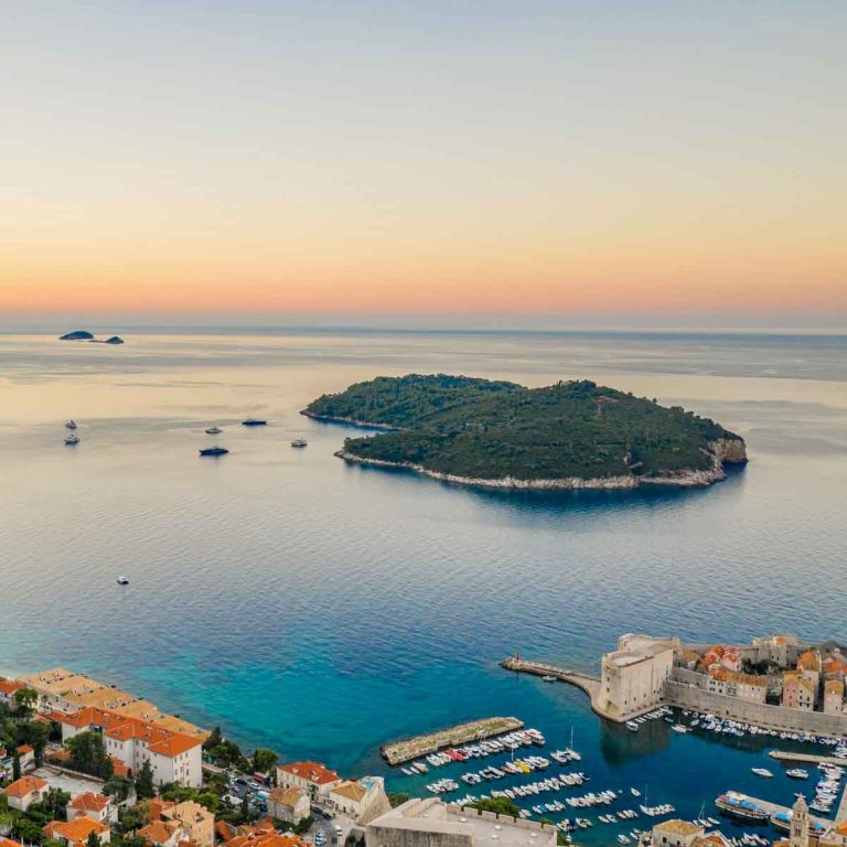 Aerial view over the rooftops and Old Town of Dubrovnik to Lokrum Island with boats moored nearby - my tips for a day trip visiting Lokrum with kids