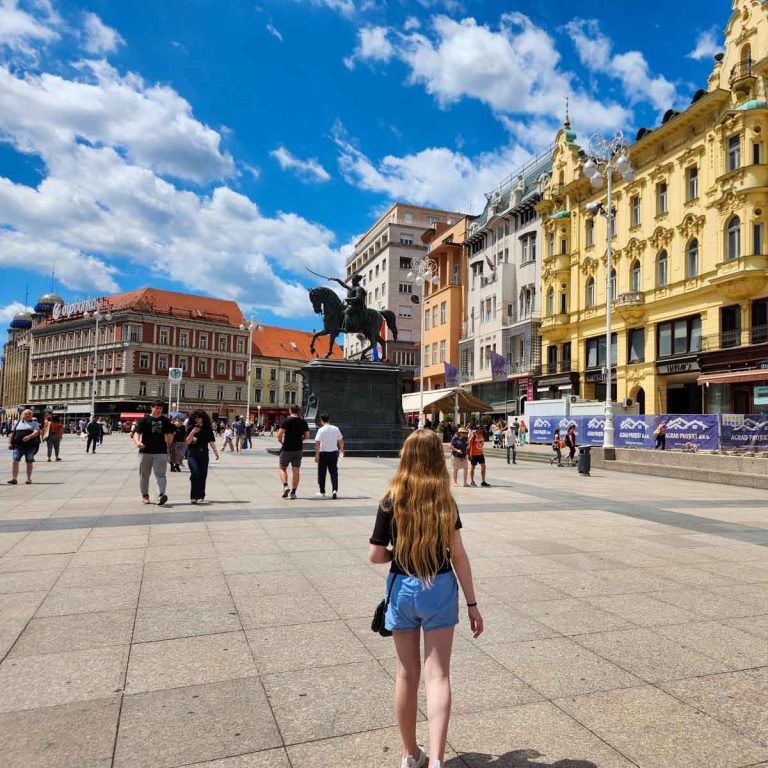 My daughter in Ban Josip Jelačić square looking at the colourful buildings and statue of Jelacic on his horse - my tips on the best things to do in Zagreb with kids