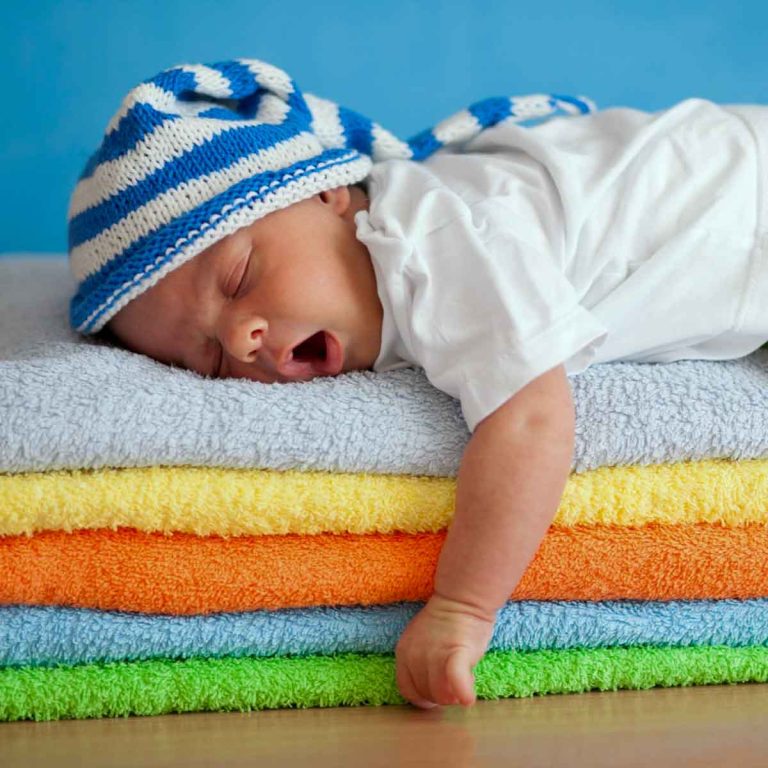Yawning baby sleeping on a pile of towels - my tips on how to beat baby jetlag