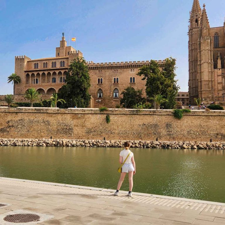 My daughter stands in front of La Almudaina Palace in Palma - visiting the island capital is one of my top things to do in Mallorca with kids