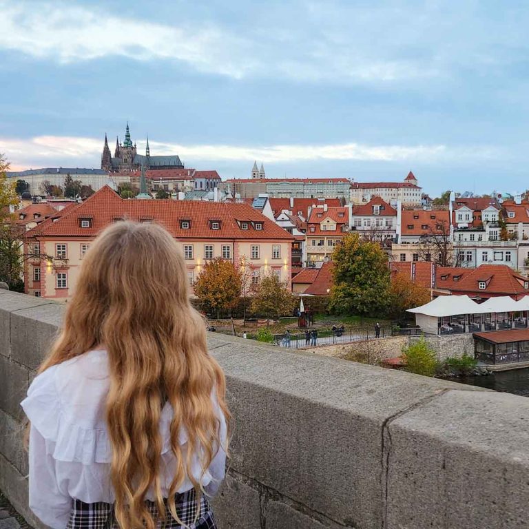My daughter looks towards Prague cathedral and castle from the Charles bridge - some of the unmissable things to do in Prague with kids