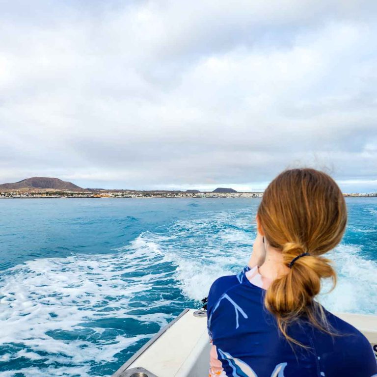 My daughter looks back to the coast of Fuerteventura as we set off on a boat tour dolphin watching in Fuerteventura