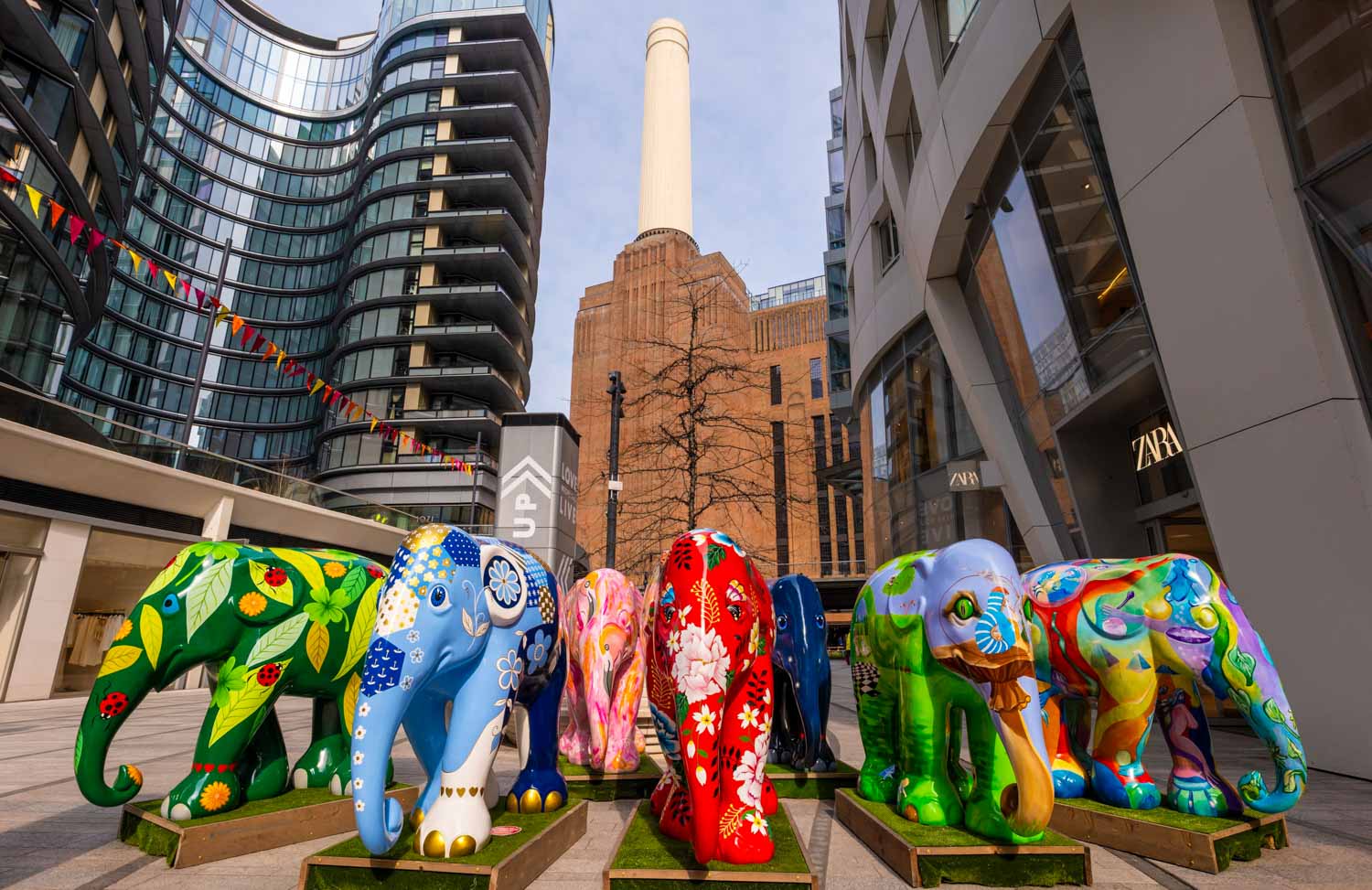 A line of elephant statues in front of Battersea Power Station, with one of the towers visible - the free Easter trail is one of the fun things to do at Easter in London with kids