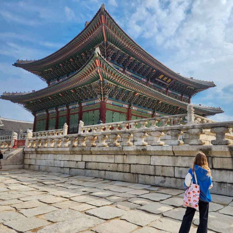 My daughter looks towards the painted roof of one of the buildings in Gyeongbokgung Palace in Seoul - my tips for South Korea with kids