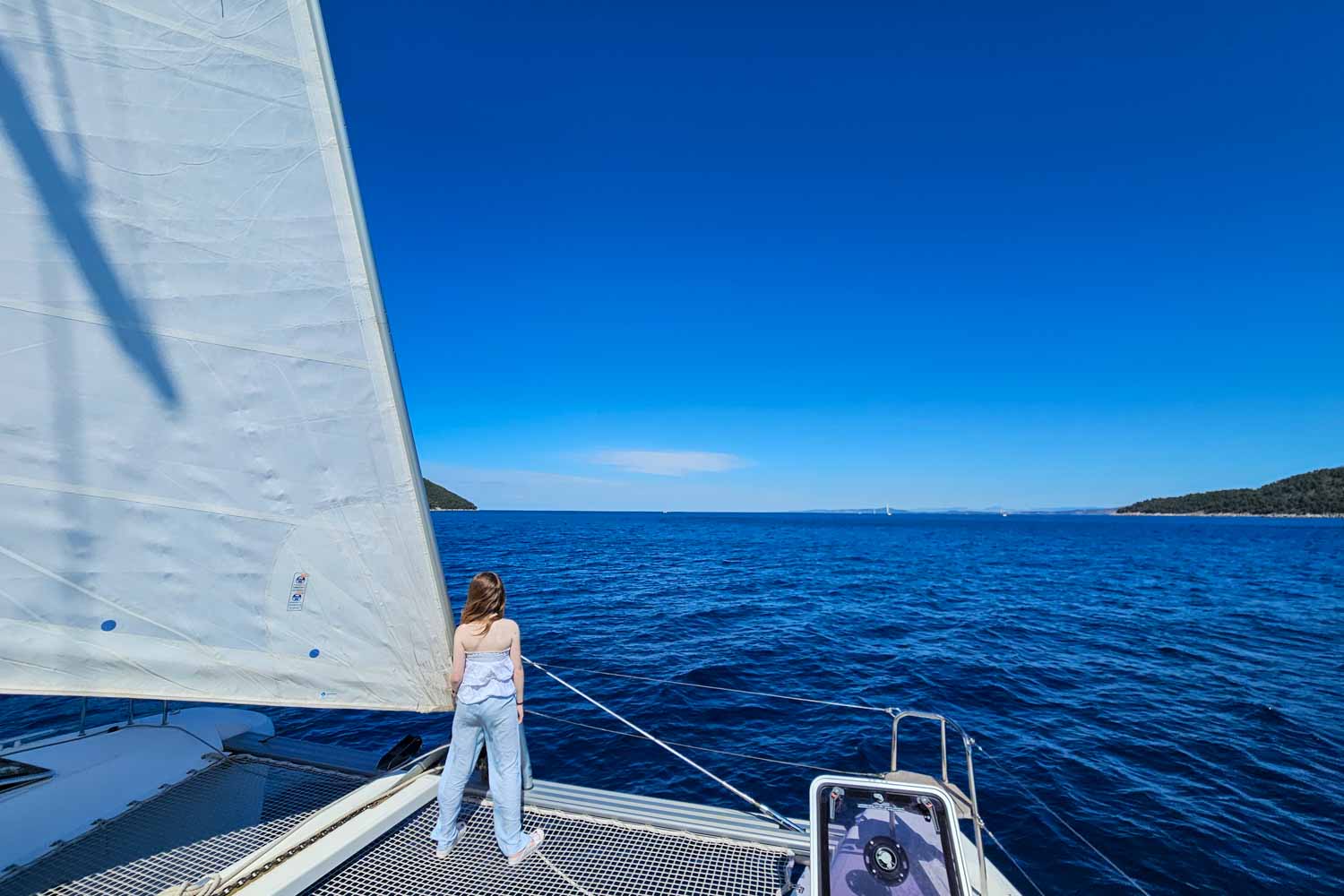 View of my daughter standing on the nets at the front of our Lagoon 42 catamaran during a More Sailing Croatia holiday - my review of a Croatia sailing holiday with kids
